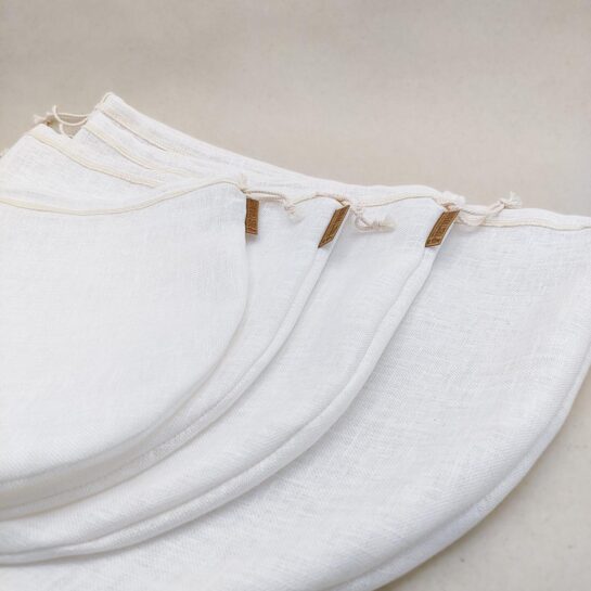 NECTARBAR-Filterbeutel-Leinen-Alle Die vier unterschiedlich großen weißen Leinenfilterbeutel liegen aufgereiht, das braune Nectarbar Etikett ist gut sichtbar.