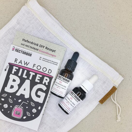 NECTARBAR_Enzymset-200l-Close Zwei 20ml Fläschchen liegen auf einem Filterbeutel aus leinen, daneben liegt die Anleitung zur Herstellung von Haferdrink in der Nahaufnahme.